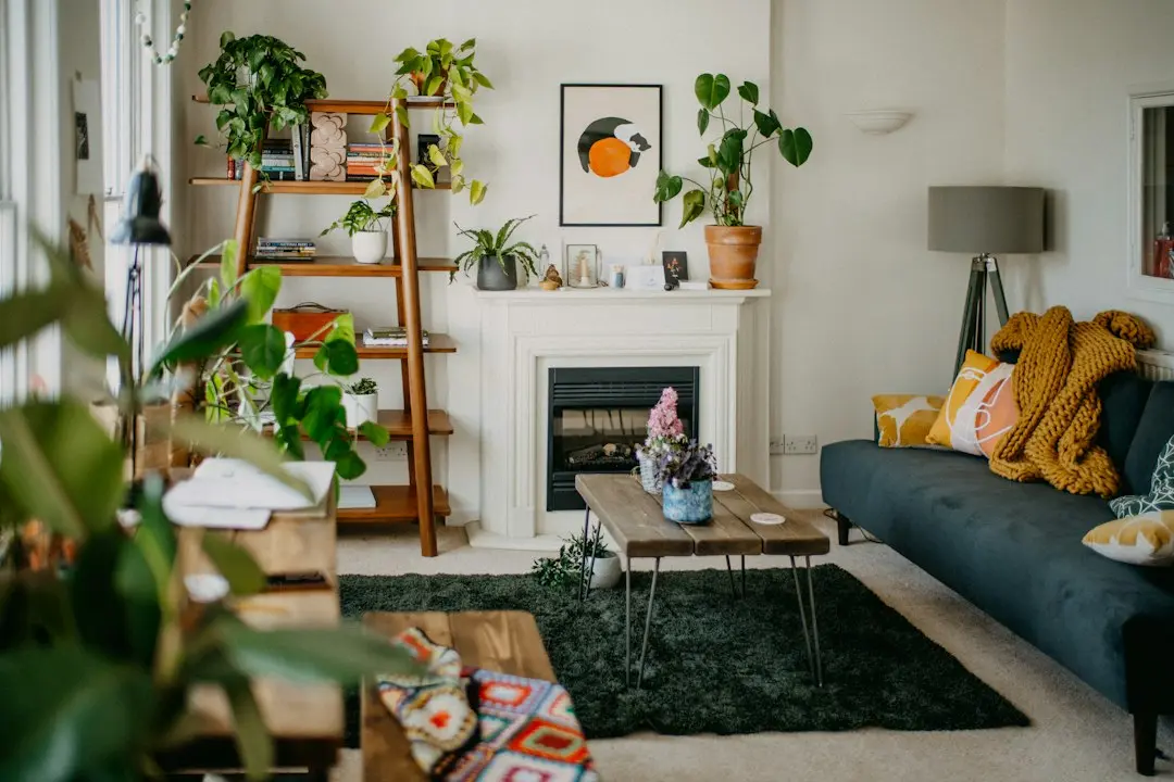 Living room with a dark blue sofa, a wooden coffee table, a fireplace and shelves full of plants